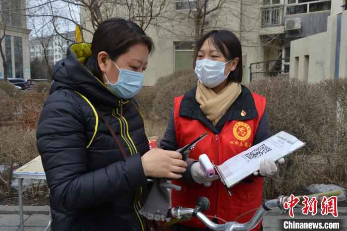 李悦为社区居民测体温，帮助居民登记扫码信息 张桂芹 摄