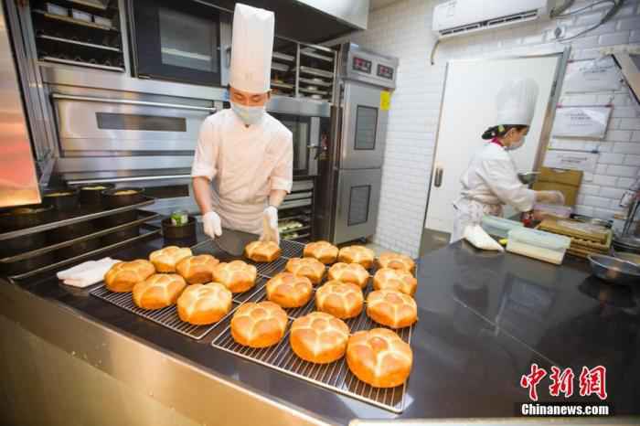 资料图：2月20日，山西太原一面包店，糕点师正在制作糕点。山西餐饮业商家通过线下门店民众进门量体温、消毒、留联系方式，线上外卖配送等多种方式积极防控疫情，逐步开始复工。 /p中新社记者 张云 摄