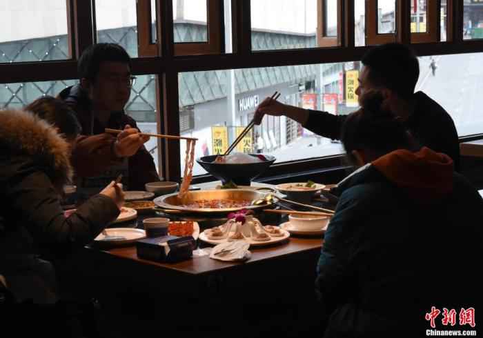 资料图：3月14日，在做好疫情防控的同时，重庆部分餐厅有序恢复堂食供应，不少市民戴着口罩前往排队吃火锅。 周毅 摄