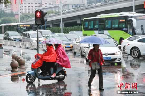 资料图：市民冒雨出行。/p中新社记者 贾天勇 摄