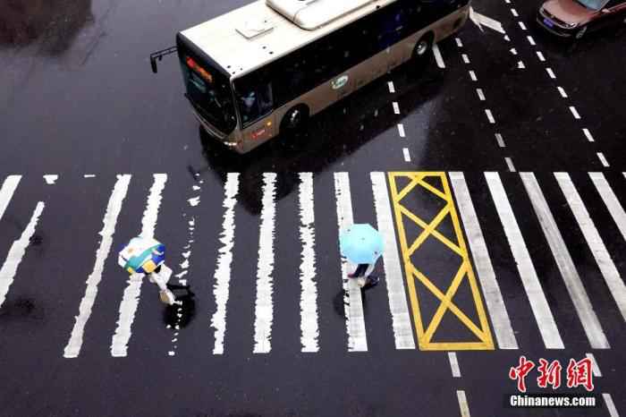 资料图：市民在风雨中出行。/p中新社记者 王中举 摄