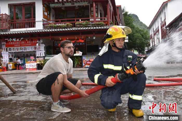 Mathias与阳朔西街消防站队员一起使用消防水带“灭火”。　叶晴 摄