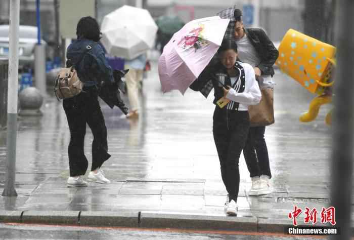 资料图：市民顶风冒雨出行。
/p中新社记者 张瑶 摄