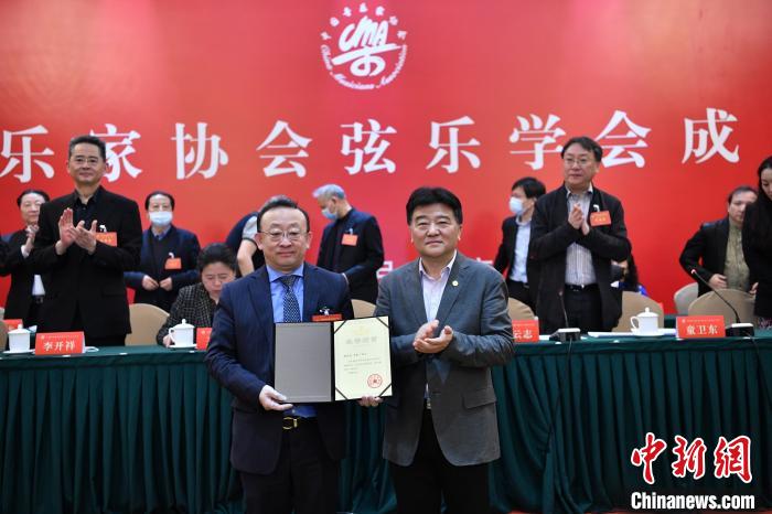 中国音协分党组书记、驻会副主席韩新安(右)为小提琴演奏家、中央歌剧院院长刘云志(左)颁发弦乐学会会长聘书。中国音协供图